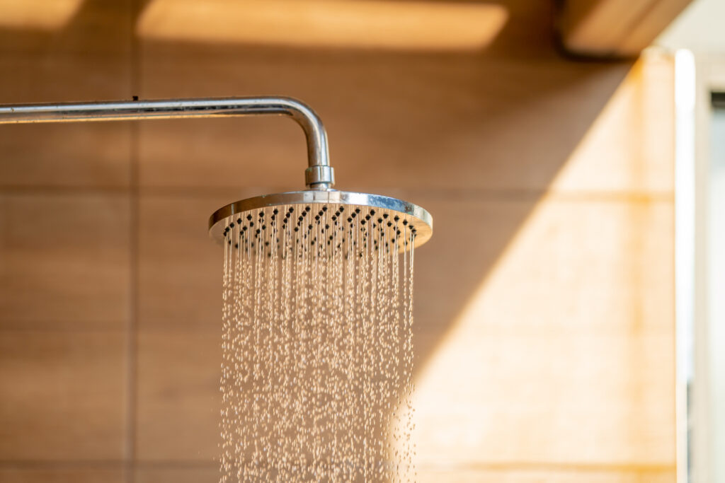 A shower head sprays soothing water in a wood-paneled room for can-i-take-a-bath-or-shower-after-acupuncture blog.